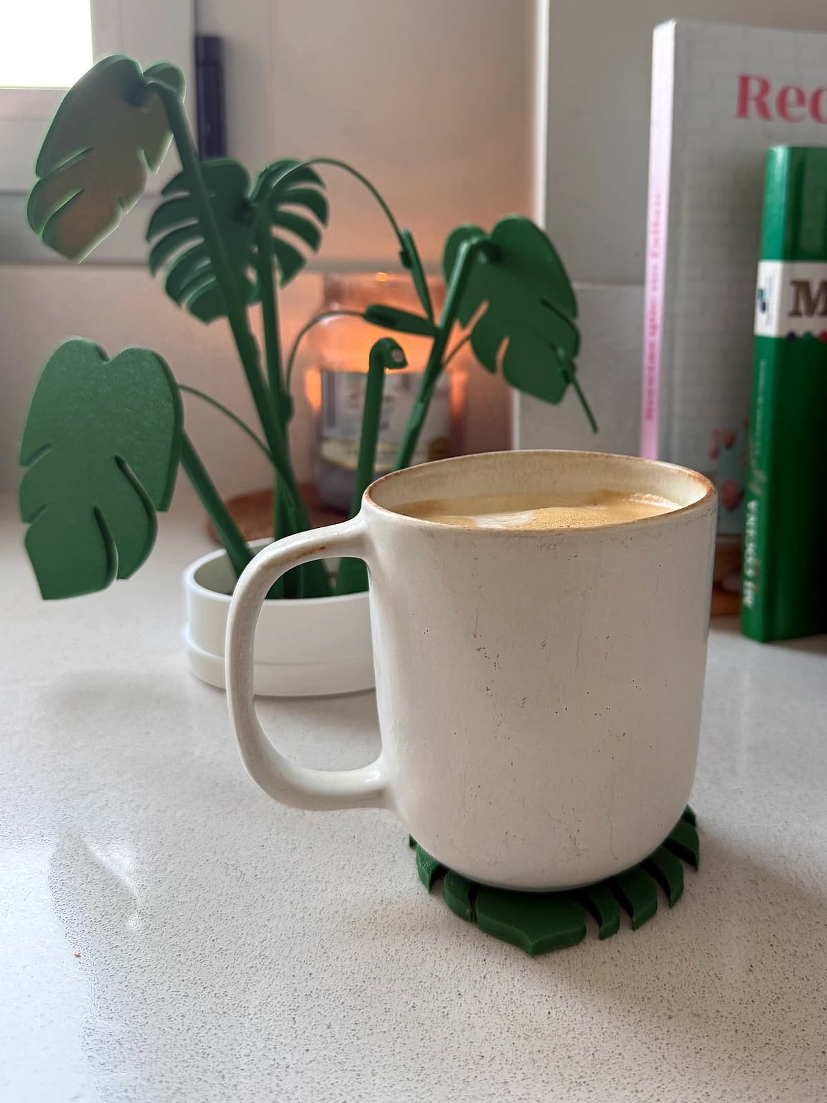 Posavasos con silueta de hojas de Monstera recogidos en maceta junto a taza de café