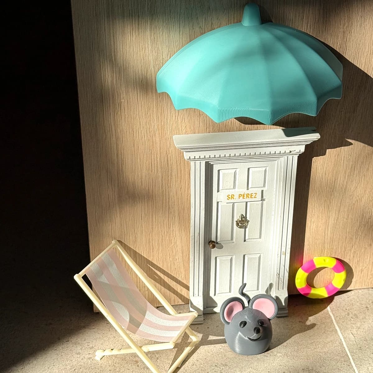 Composición en miniatura con puerta rotulada, sombrilla y accesorios de playa